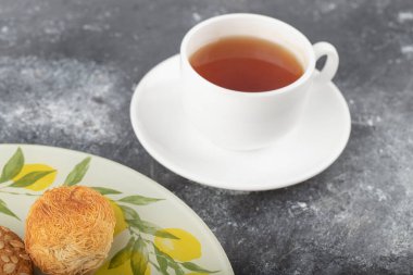 Tabakta tatlı abur cuburlar ve arka planda beyaz bir fincan çay. Yüksek kalite fotoğraf