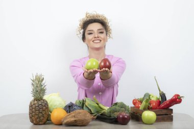 Kıvırcık kadın masada oturmuş lezzetli meyveler tutuyor. Yüksek kalite fotoğraf