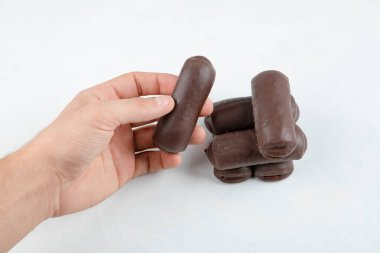 Erkek eli beyaz arka planda izole edilmiş süt kremalı çikolatalı rulo alıyor. Yüksek kalite fotoğraf