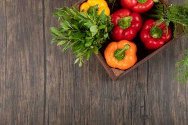 Ahşap arka planda renkli dolmalık biber ve yeşillik dolu tahta kutu. Yüksek kalite fotoğraf
