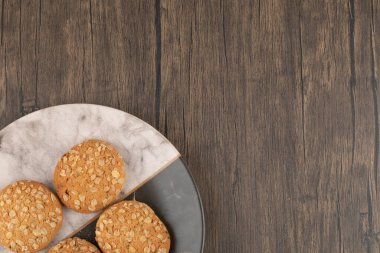 Tahta masadaki tahıllı ve tohumlu yulaf ezmeli kurabiyelerle dolu tabak. Yüksek kalite fotoğraf