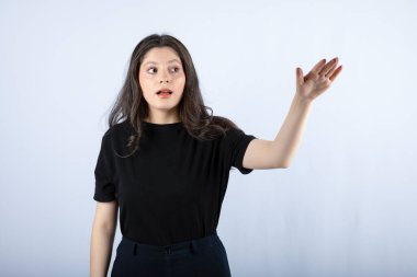 Siyah bluzlu esmer bir kızın beyaz duvarın üzerinden bir şeye baktığı görüntüsü. Yüksek kalite fotoğraf