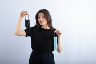 Güzel esmer kız beyaz arka planda tıbbi maskeler tutuyor. Yüksek kalite fotoğraf