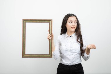 Genç bir kadın beyaz duvara resim çerçevesi dayamış. Yüksek kalite fotoğraf