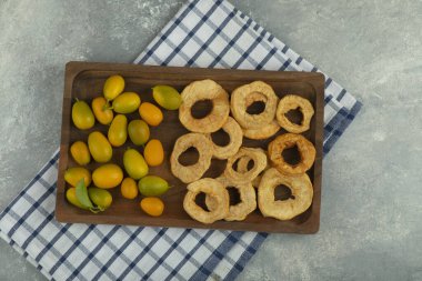 Mermer yüzeyde kurumuş elma halkaları ve kumkatlardan oluşan ahşap bir tabak. Yüksek kalite fotoğraf