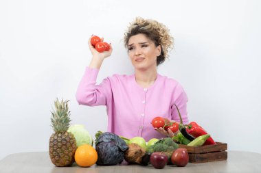 Elinde meyve masasında oturan sarışın kadın domateslerinin portresi. Yüksek kalite fotoğraf