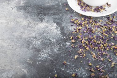 White cup of hot black tea with dried flower buds placed on a dark grey background . High quality photo