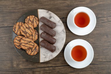 Çekirdekli kurabiyeler ve mermer tabakta bir fincan çayla çikolatalı kek. Yüksek kalite fotoğraf