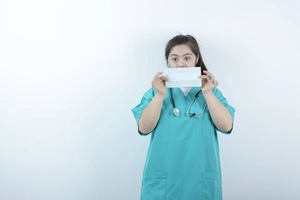 Jovem Enfermeira Com Estetoscópio Segurando Máscara Facial Médica Contra Parede — Fotografia de Stock