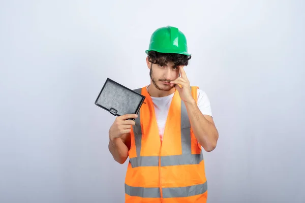 Joven Ingeniero Masculino Hardhat Verde Sosteniendo Cuaderno Negro Pie Foto — Foto de Stock