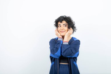 Beyaz duvara poz veren kıvırcık saçlı çekici bir kadının portresi. Yüksek kalite fotoğraf