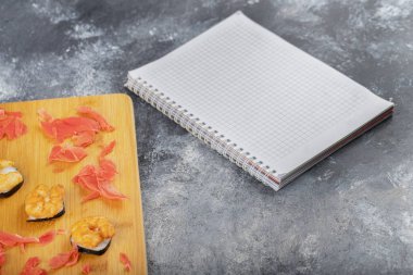 Tahta kesme tahtasına yerleştirilmiş taze, lezzetli suşi ruloları, karides ve zencefil dilimleri. Yüksek kalite fotoğraf