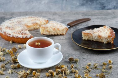 Lezzetli bir parça kek ve beyaz bir fincan sıcak çay ile siyah bir tabak. Yüksek kalite fotoğraf