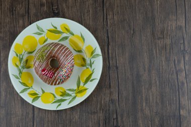 Tahta yüzeyde limon desenli tabakta çikolatalı donut. Yüksek kalite fotoğraf