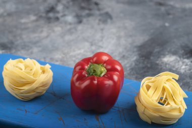 Kırmızı dolma biber ve çiğ tagliatelle makarnası mavi kesim tahtasında. Yüksek kalite fotoğraf