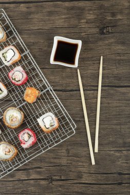 Çeşitli suşi çeşitleri, yemek çubukları ve soya sosuyla ahşap arka planda. Yüksek kalite fotoğraf