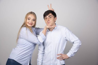 Gri arka planda erkek arkadaşıyla oynayan genç bir kadın. Yüksek kalite fotoğraf