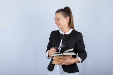 Beyaz arka planda duran kitapları olan genç bir kız öğrencinin portresi. Yüksek kalite fotoğraf