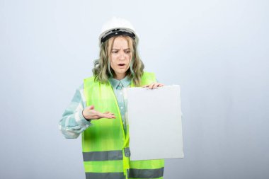 Güzel bayan mühendisin beyaz duvarın üzerinde boş tuval tutarken çekilmiş fotoğrafı. Yüksek kalite fotoğraf