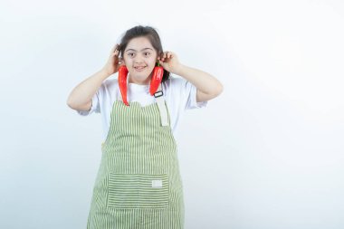 Kareli önlüğün içinde duran ve elinde iki kırmızı acı biber tutan genç ve güzel bir kız. Yüksek kalite fotoğraf