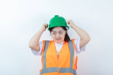 Beyaz duvarda yeşil kaskını takan genç bir kadın inşaat işçisi. Yüksek kalite fotoğraf