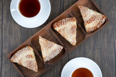 Tahta bir tahtanın üzerinde dilimlenmiş lezzetli pastayla iki fincan sıcak çay. Yüksek kalite fotoğraf