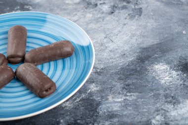 Taştan bir arka plana yerleştirilmiş çikolata çubuklu mavi tabak. Yüksek kalite fotoğraf