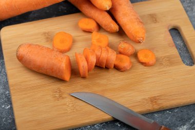 Tam ve dilimlenmiş taze ve tatlı havuçlar mermer bir zemine yerleştirilmiş bıçakla. Yüksek kalite fotoğraf