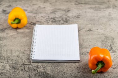 Taş yüzeyde iki taze dolma biber ve boş defter. Yüksek kalite fotoğraf