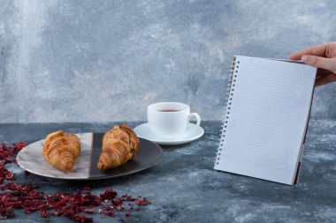 Dişi el ele tutuşması, ayçöreği olan bir fincan çayın yanında bir defter açtı. Yüksek kalite fotoğraf