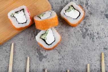 Somonlu suşi, füme yılan balığı, avokado, krem peynir ve tek kullanımlık ahşap çubuklar. Yüksek kalite fotoğraf