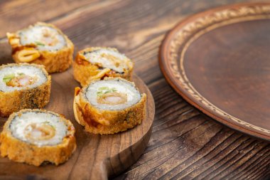 Tahta kesme tahtasına yerleştirilmiş füme tavuk göğsünden yapılmış taze suşi ruloları. Yüksek kalite fotoğraf