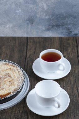 Tahta masaya bir fincan siyah çay ile bir tabak lezzetli turta. Yüksek kalite fotoğraf