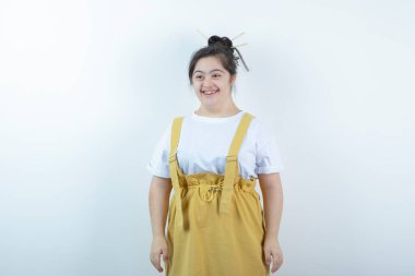 Beyaz duvarın karşısında duran ve gülümseyen genç ve güzel bir kız modeli. Yüksek kalite fotoğraf