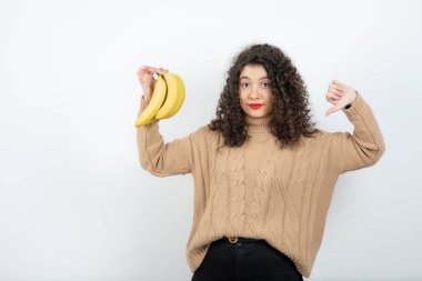 Kıvırcık genç bir kadının muz tutarken çekilmiş fotoğrafı. Yüksek kalite fotoğraf