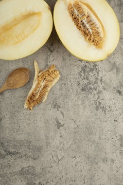 Ahşap kaşıkla mermer yüzeyde yarım lezzetli sarı kavunlar. Yüksek kalite fotoğraf