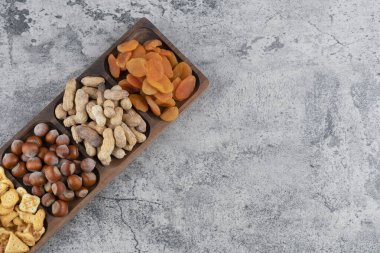 Tahta tabak dolusu fındık, kraker ve mermer yüzeyde kurutulmuş kayısı. Yüksek kalite fotoğraf