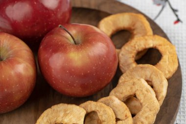 Ahşap bir tabak kırmızı elma ve masa örtüsünün üzerinde kurumuş halkalar. Yüksek kalite fotoğraf