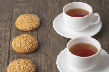 Tohumlu lezzetli yulaf ezmeli bisküviler ve ahşap masada bir fincan sıcak çay. Yüksek kalite fotoğraf