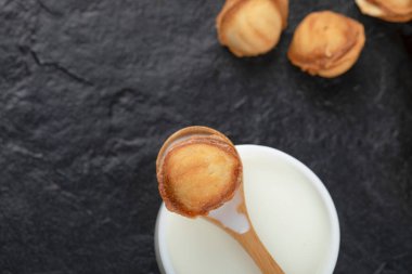 Siyah arka planda kaşık ve ceviz kurabiyeli bir fincan süt. Yüksek kalite fotoğraf