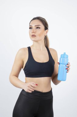 Mavi su şişesi ayakta duran genç atletik kadın portresi. Yüksek kalite fotoğraf