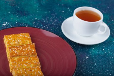 Renkli bir masaya konmuş bir fincan siyah çay ile bir tabak tatlı kraker. Yüksek kalite fotoğraf