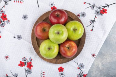 Masa örtüsündeki ahşap bir tabakta izole edilmiş yeşil ve kırmızı olgun elmalar. Yüksek kalite fotoğraf