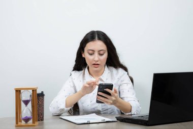 İş kadını masada oturuyor ve akıllı telefonlara bakıyor. Yüksek kalite fotoğraf