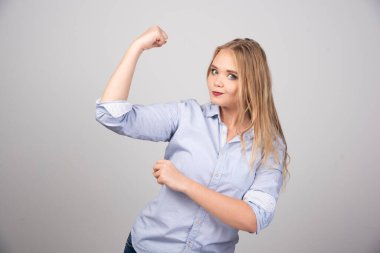 Genç, güzel sarışın kadın ayakta ve kol kaslarını gösteriyor. Yüksek kalite fotoğraf