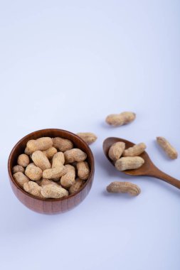 Ahşap kase dolusu soyulmamış fıstık ve beyaz arka planda kaşık. Yüksek kalite fotoğraf