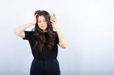 Beyaz arka planda uyuyan çalar saati olan genç bir kız resmi. Yüksek kalite fotoğraf