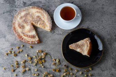 Lezzetli bir parça kek ve beyaz bir fincan sıcak çay ile siyah bir tabak. Yüksek kalite fotoğraf