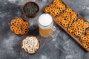 Bir kase tuzlu kraker, siyah ayçiçeği tohumu ve mermer arka planda bir kupa bira. Yüksek kalite fotoğraf