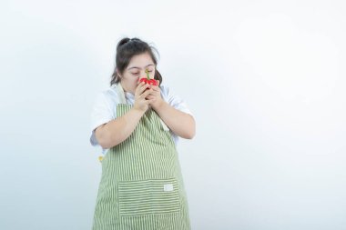 Kareli önlüğün içinde duran ve kırmızı dolma biber yiyen genç ve güzel bir kız. Yüksek kalite fotoğraf